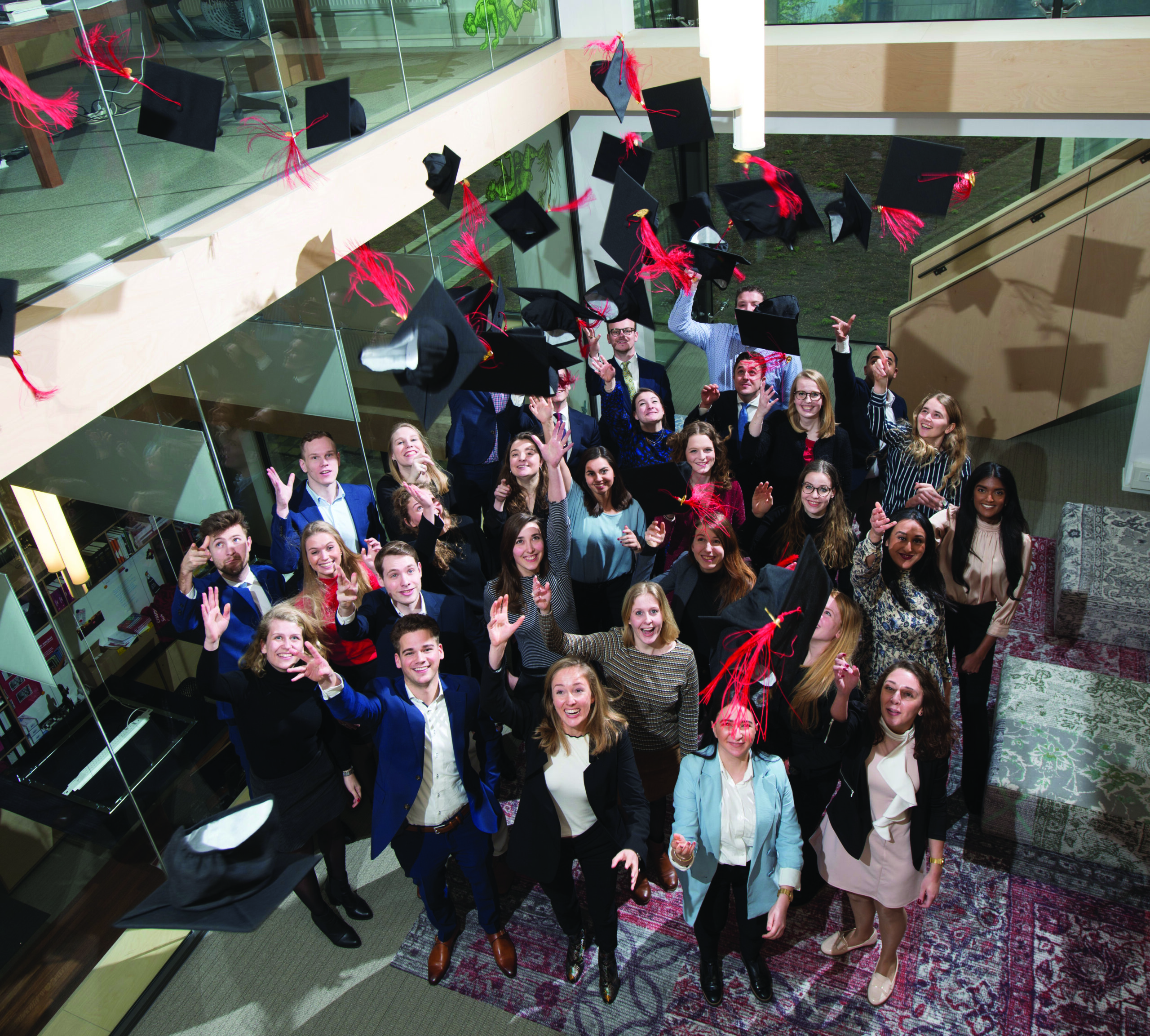 Groepsfoto van afgestudeerde studenten die hoed in de lucht gooien